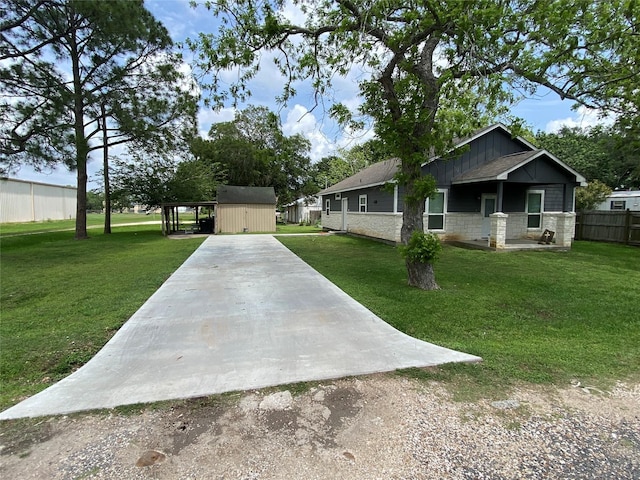 view of front of property with a storage shed, concrete driveway, a front lawn, board and batten siding, and fence