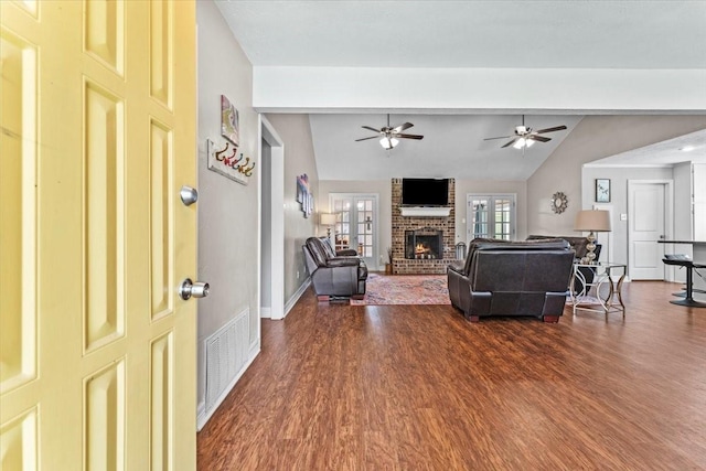living area featuring ceiling fan, lofted ceiling with beams, a fireplace, dark wood finished floors, and visible vents