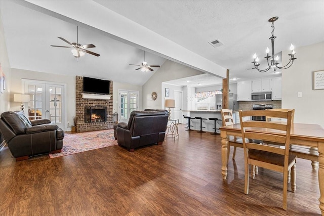 dining space with a brick fireplace, french doors, lofted ceiling, dark wood-type flooring, and visible vents