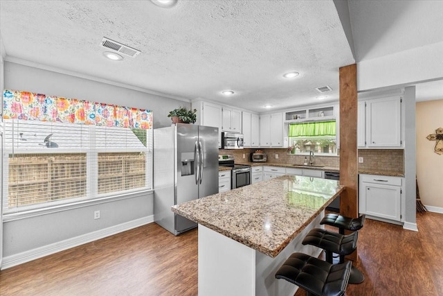 kitchen with stainless steel appliances, visible vents, dark wood-style floors, and a sink