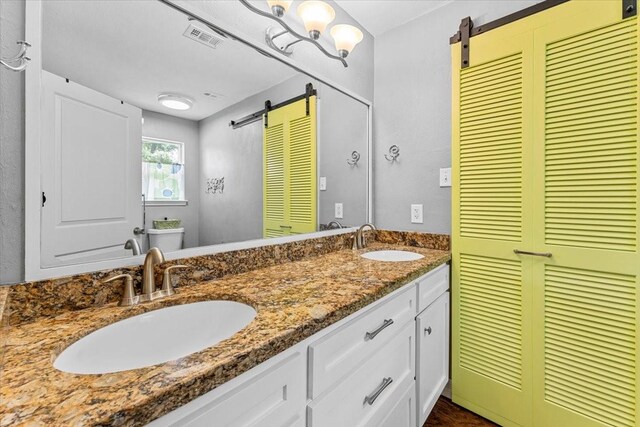 bathroom with a sink, a closet, toilet, and visible vents