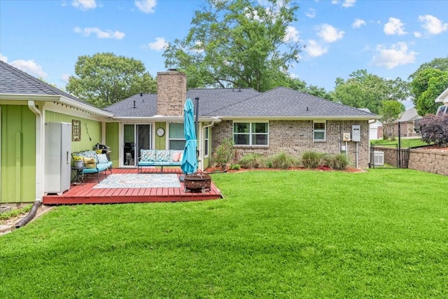 back of house with a fire pit, a wooden deck, a yard, and a chimney