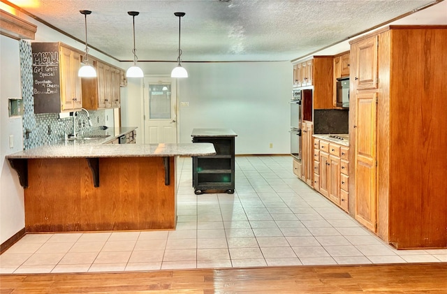 200 Greenwood Dr, Beaumont, TX 77705 - kitchen with backsplash, a sink, a peninsula, light wood-style flooring, and a breakfast bar area