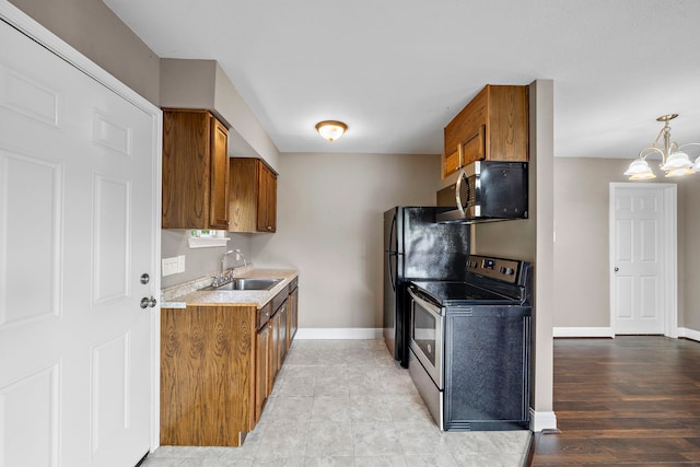 1111 Robert St, Pearland, TX 77581 - kitchen with appliances with stainless steel finishes, brown cabinets, a sink, a chandelier, and baseboards