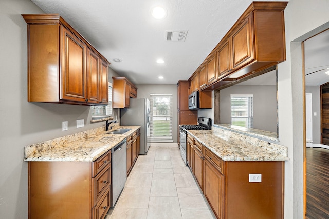 1111 Robert St, Pearland, TX 77581 - kitchen featuring stainless steel appliances, a sink, light stone counters, recessed lighting, and brown cabinets