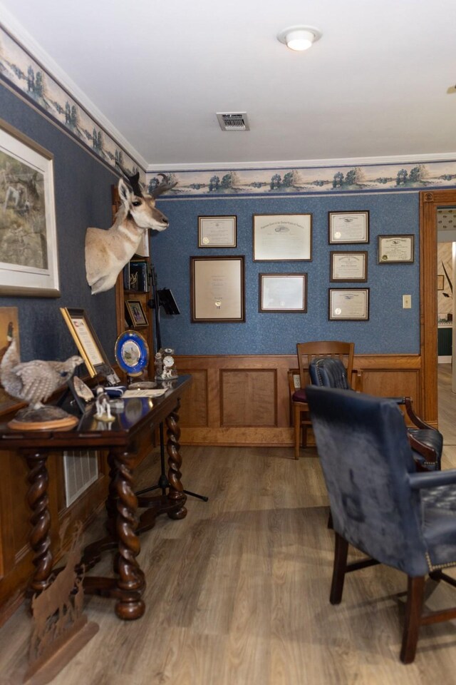 office space featuring wainscoting, wood finished floors, visible vents, and crown molding