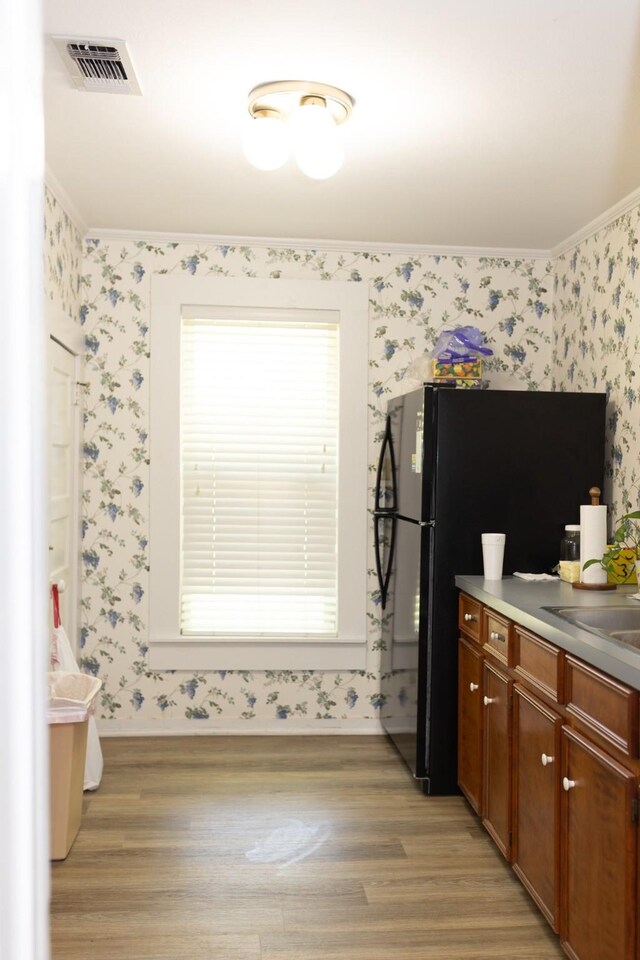 kitchen with wallpapered walls, visible vents, light wood finished floors, and baseboards
