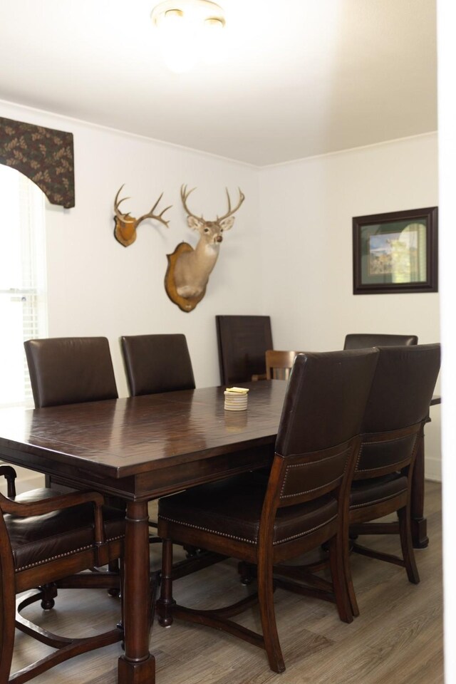 dining area with light wood finished floors and crown molding