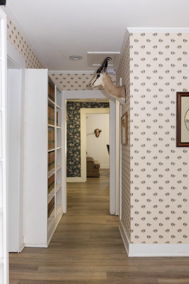 hallway featuring baseboards, wood finished floors, and wallpapered walls