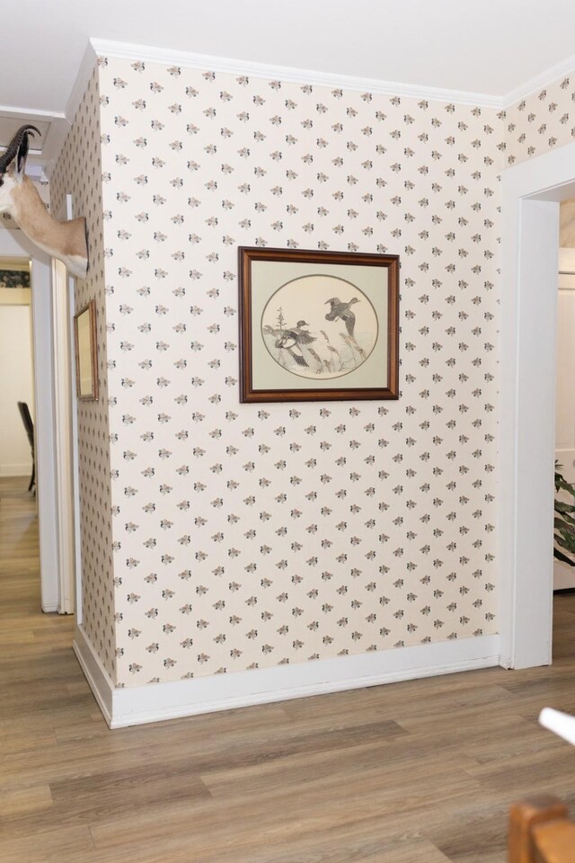 interior details featuring wallpapered walls, wood finished floors, baseboards, and ornamental molding