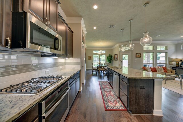 kitchen with open floor plan, dark brown cabinetry, stainless steel appliances, ornamental molding, and dark wood-type flooring
