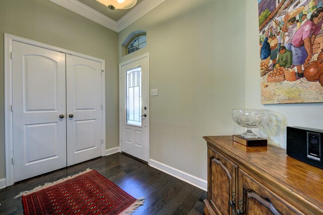 foyer with crown molding, baseboards, and dark wood-style flooring