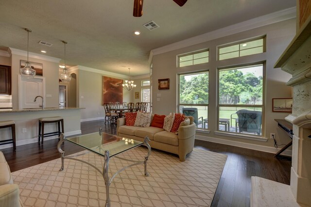 living area featuring baseboards, visible vents, recessed lighting, wood finished floors, and ornamental molding