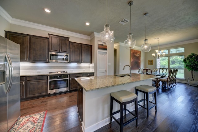 kitchen featuring visible vents, a sink, appliances with stainless steel finishes, and crown molding