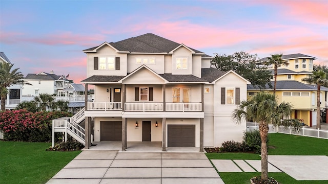 raised beach house with covered porch, driveway, a lawn, stairway, and an attached garage