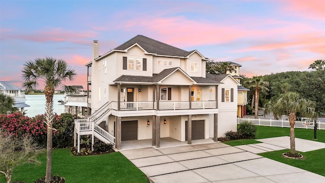beach home with driveway, a chimney, a front yard, a garage, and fence