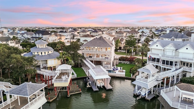 aerial view at dusk featuring a water view and a residential view