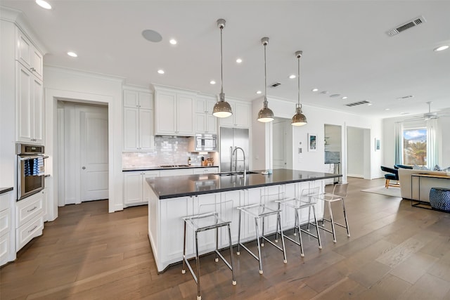 kitchen with decorative backsplash, visible vents, dark countertops, built in appliances, and white cabinetry