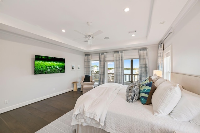 bedroom with baseboards, a tray ceiling, wood finished floors, and access to exterior