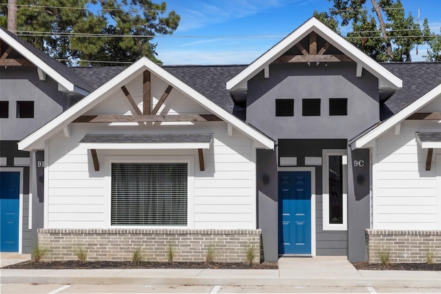 doorway to property with a shingled roof and brick siding