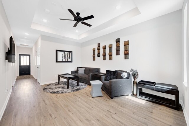 living area featuring recessed lighting, baseboards, light wood finished floors, and a raised ceiling