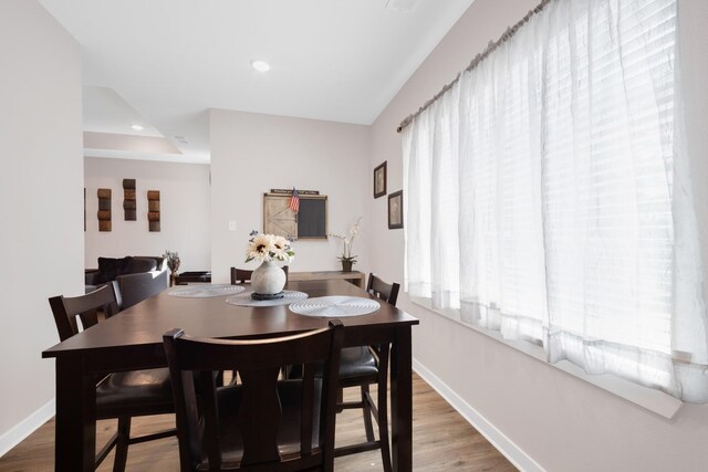 dining space featuring baseboards, wood finished floors, and recessed lighting
