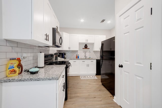 kitchen featuring white cabinets, open shelves, a sink, black appliances, and tasteful backsplash
