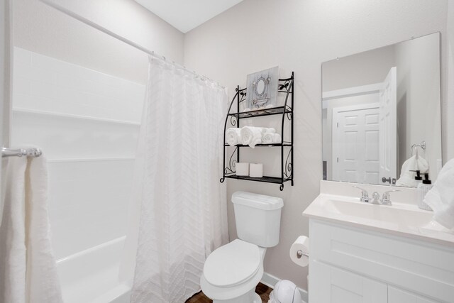 bathroom featuring toilet, vanity, and baseboards