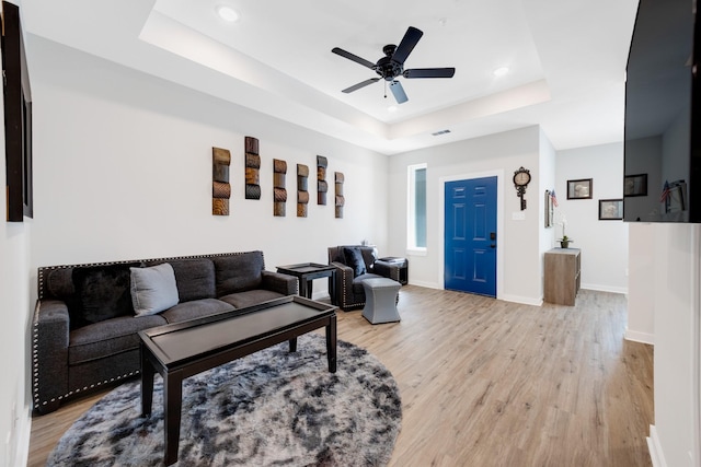 living area featuring recessed lighting, a tray ceiling, a ceiling fan, light wood-type flooring, and baseboards