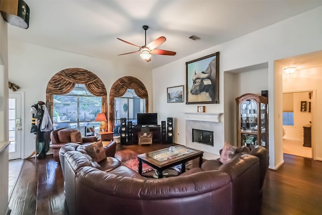 living room featuring a glass covered fireplace, wood finished floors, visible vents, and a ceiling fan