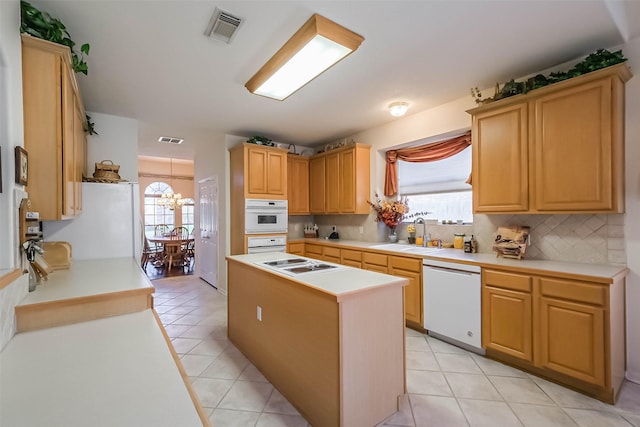 kitchen with backsplash, visible vents, a sink, and white appliances