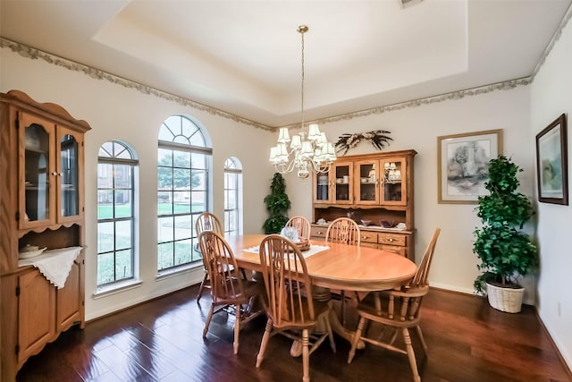dining area with plenty of natural light, dark wood-type flooring, a notable chandelier, and a raised ceiling