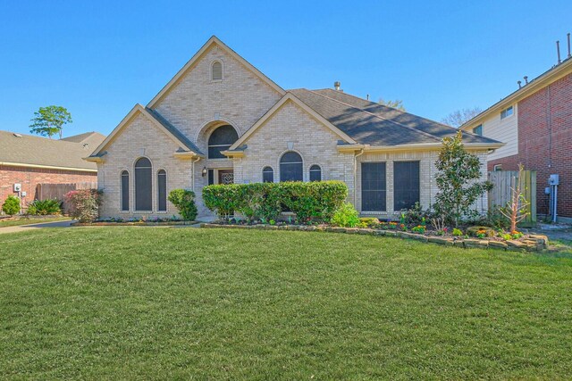 french country inspired facade featuring fence, brick siding, and a front yard