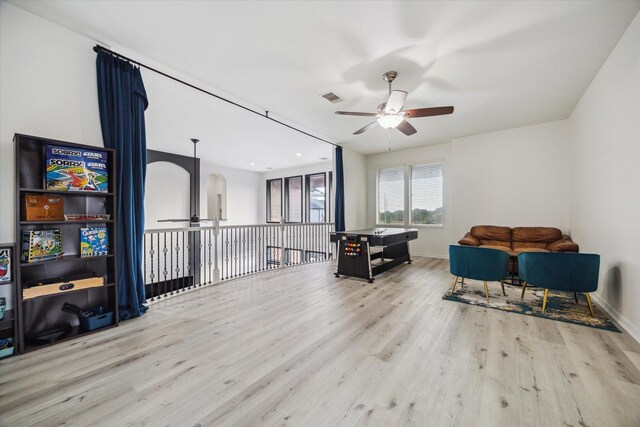 living area featuring a ceiling fan, visible vents, arched walkways, wood finished floors, and baseboards