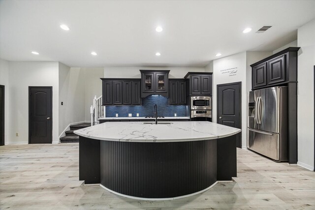 kitchen featuring light wood-type flooring, a sink, appliances with stainless steel finishes, and tasteful backsplash