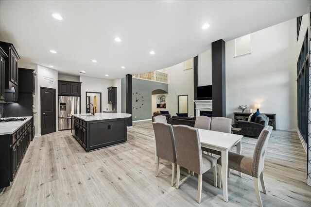 dining area with arched walkways, recessed lighting, light wood finished floors, and a fireplace