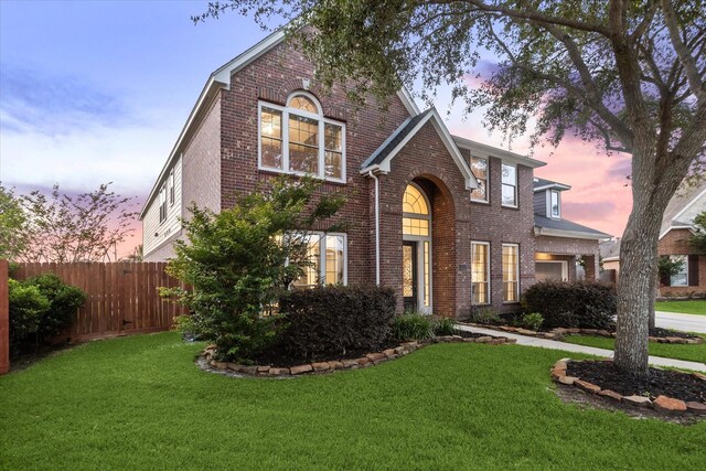 traditional-style home with fence, a front lawn, and brick siding
