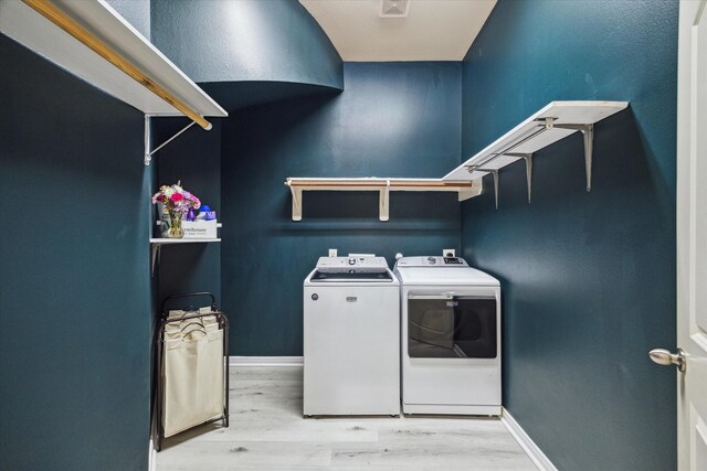 laundry area featuring baseboards, separate washer and dryer, laundry area, and wood finished floors