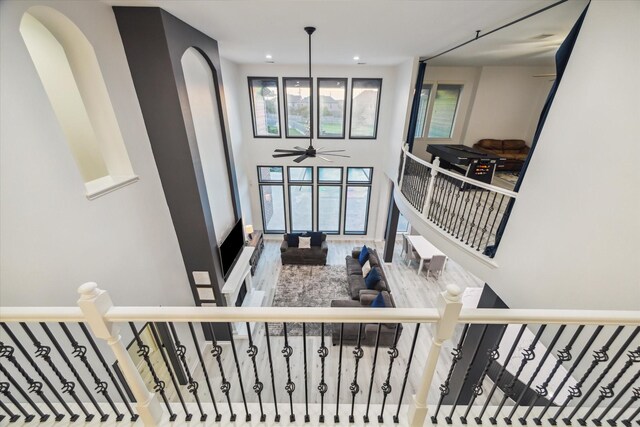 stairs with recessed lighting, a ceiling fan, a towering ceiling, and arched walkways