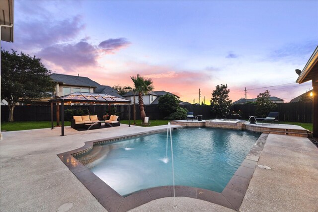 pool at dusk with a patio, an outdoor hangout area, and a fenced backyard