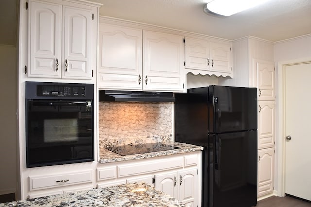 kitchen featuring white cabinets, decorative backsplash, light stone countertops, under cabinet range hood, and black appliances
