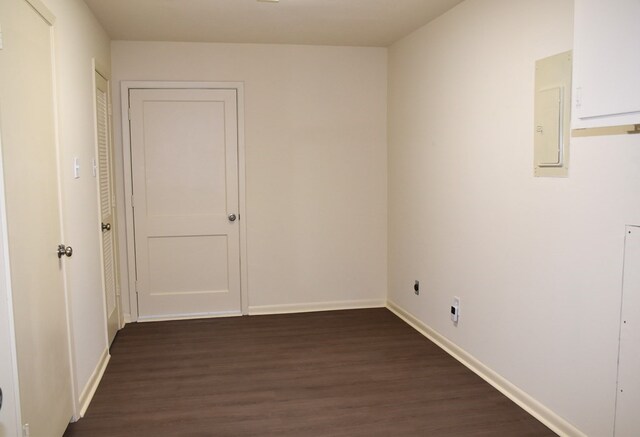 unfurnished room featuring baseboards, electric panel, and dark wood-style floors