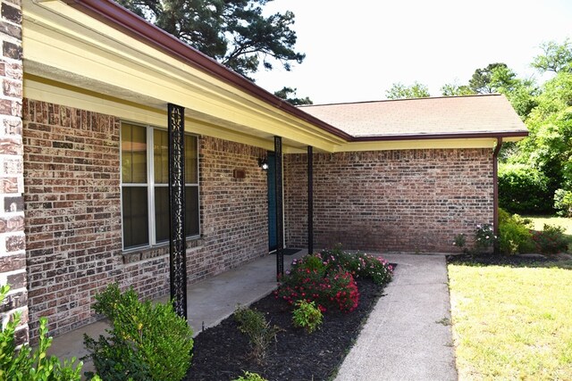 entrance to property with a lawn and brick siding