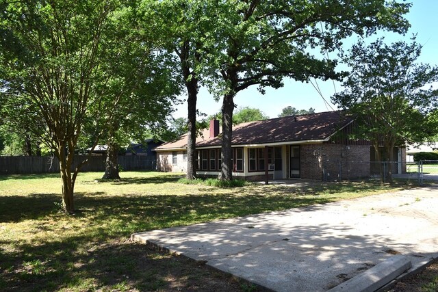 rear view of house featuring fence, a lawn, and a chimney