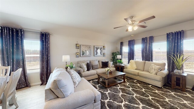living room featuring lofted ceiling, wood finished floors, a ceiling fan, and baseboards
