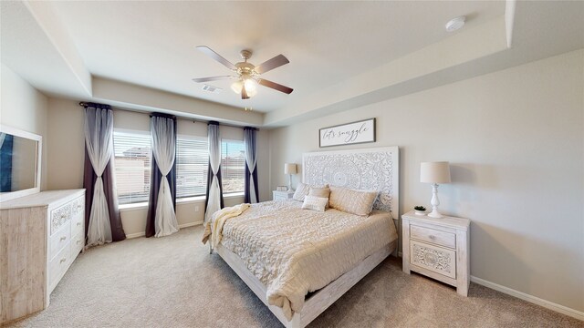 bedroom featuring light colored carpet, baseboards, a tray ceiling, and visible vents