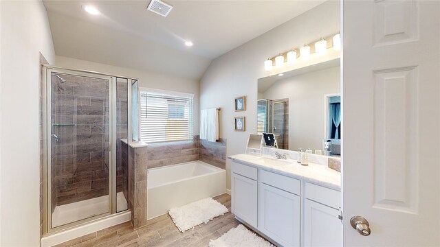 full bathroom featuring a shower stall, vaulted ceiling, visible vents, wood finished floors, and vanity