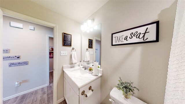 bathroom featuring baseboards, wood finished floors, vanity, and toilet