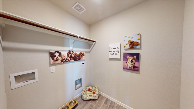 clothes washing area with hookup for an electric dryer, baseboards, visible vents, wood finished floors, and laundry area