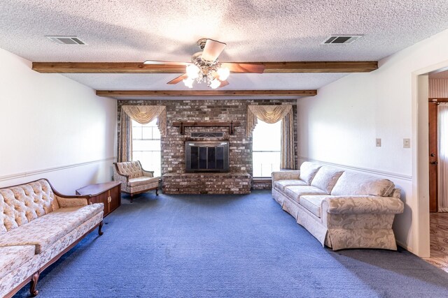 living area with beamed ceiling, a textured ceiling, and carpet